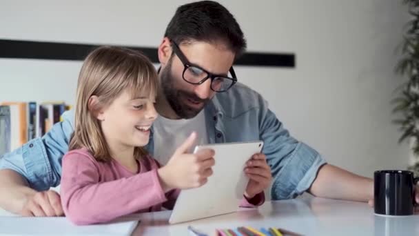 Bonito pai jovem com sua filha usando eles tablet digital em casa . — Vídeo de Stock