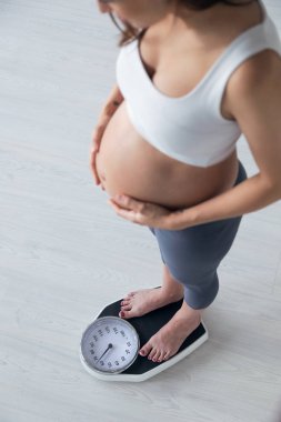 Pretty genç hamile kadın evde terazi üzerinde duran.