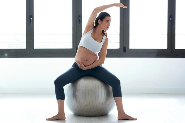 Mujer joven embarazada haciendo ejercicios de relajación con una pelota de pilates de fitness en casa . — Foto de Stock