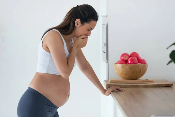 Mujer joven embarazada asqueada que sufre de náuseas por la mañana en casa —  Fotos de Stock