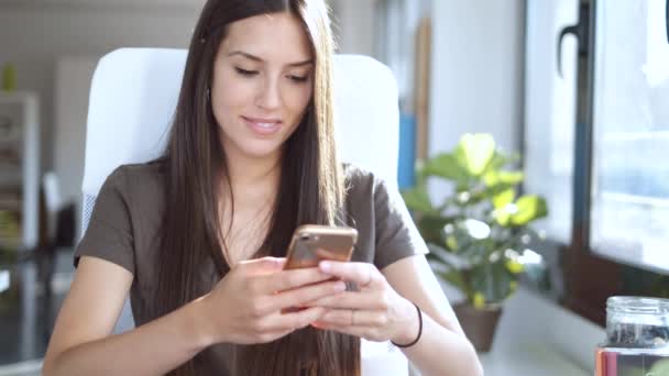 Ofiste Otururken Cep Telefonu Ile Mesaj Gönderen Gülümseyen Genç Kadını — Stok video