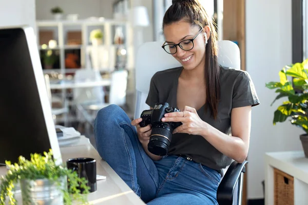 スタジオに座りながらカメラで撮った写真を見直すプロの若い写真家. — ストック写真