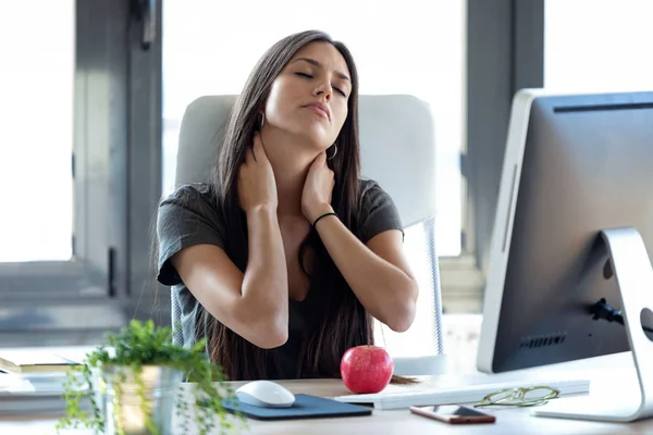 Müde junge Geschäftsfrau mit Nackenschmerzen bei der Arbeit mit dem Computer im Büro. — Stockfoto
