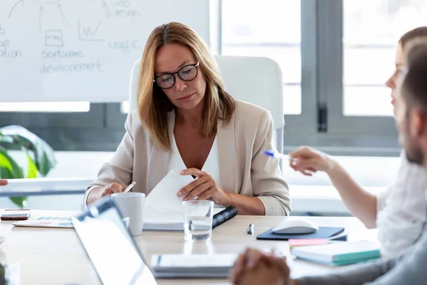 Koncentrerad affärskvinna granska hennes anteckningar för möte om Coworking rymden. — Stockfoto