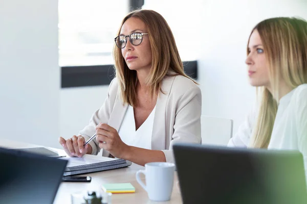 Δύο συγκεντρωμένη επιχείρηση γυναίκα ακούγοντας τους συνεργάτες της σε coworking χώρο. — Φωτογραφία Αρχείου