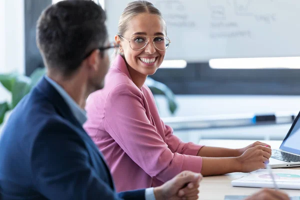 Sorrindo jovem empresária olhando e ouvindo seu parceiro no espaço de co-trabalho . — Fotografia de Stock