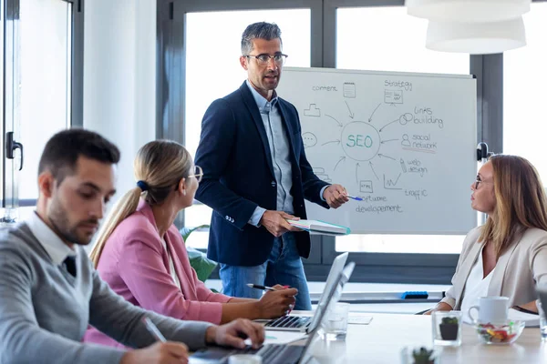 Handsome businessman explaining a project to his colleagues on coworking place. — Stock Photo, Image