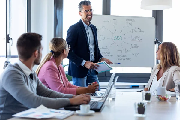 Bonito empresário explicando um projeto para seus colegas em co-working place . — Fotografia de Stock