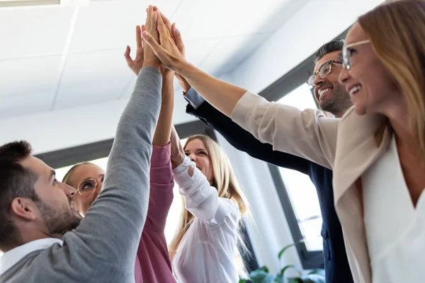 Grupo de jóvenes empresarios exitosos que levantan la mano derecha en el lugar de coworking . — Foto de Stock