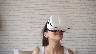 Evde yatakta otururken sanal gerçeklik gözlüğü kullanan güzel genç hamile kadının videosu.