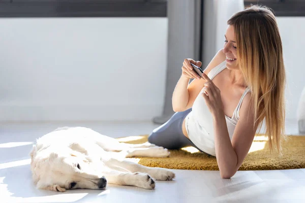 自宅で床に滞在しながら、彼女の犬に写真を撮るかなり若い女性. — ストック写真