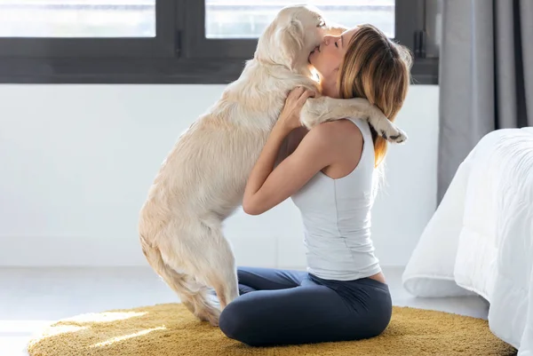 Pretty ung kvinna kramar sin hund när du sitter på golvet hemma. — Stockfoto