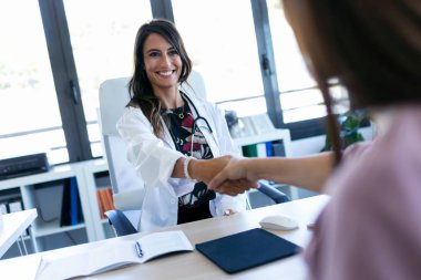 Klinikte ilk ziyarette el sıkışırken genç kadın doğum uzmanı ve hamile kadın.