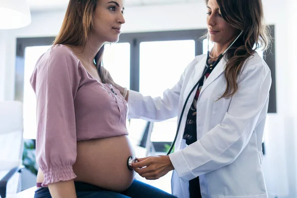 クリニックで彼女の妊娠中の患者の心拍赤ちゃんをチェックかなり若い女性婦人科医. — ストック写真