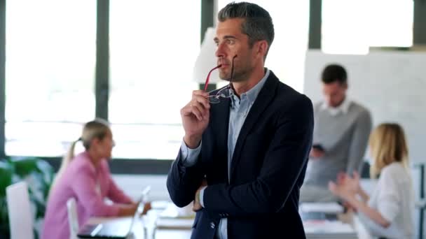 Hombre de negocios guapo mirando hacia los lados mientras piensa en el lugar de coworking. Finalmente, está mirando a la cámara. . — Vídeo de stock