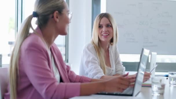 Deux jeunes femmes d'affaires souriantes parlent tout en travaillant avec un ordinateur portable sur l'espace de coworking . — Video