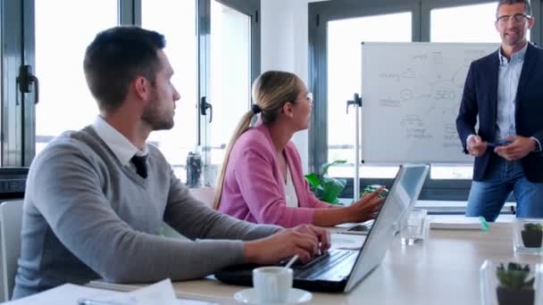 Beau businessman expliquant un projet à ses collègues sur le lieu de coworking . — Video