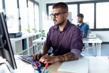 Modern başlangıç ofisinde bilgisayarla çalışan yazılım geliştiricisi.