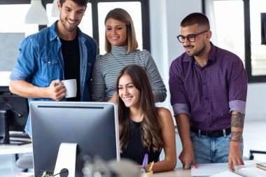 Ortak çalışma alanında iş sunumu için bilgisayarın etrafında duran başarılı iş ekibi.