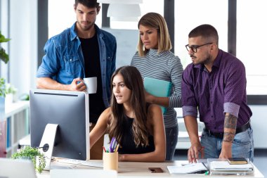 Ortak çalışma alanında iş sunumu için bilgisayarın etrafında duran başarılı iş ekibi.