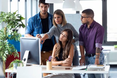 Ortak çalışma alanında iş sunumu için bilgisayarın etrafında duran başarılı iş ekibi.