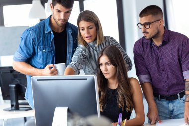 Ortak çalışma alanında iş sunumu için bilgisayarın etrafında duran başarılı iş ekibi.