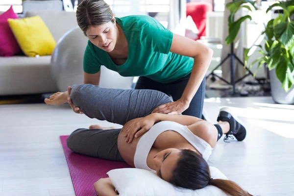 Physiotherapist helping to beautiful pregnant woman for doing pilates exercises preparing for childbirth. — Stock Photo, Image