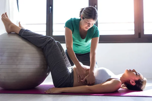 Fyzioterapeutka pomáhající krásné těhotné ženě při cvičení na Pilates s kuličková Příprava k porodu. — Stock fotografie