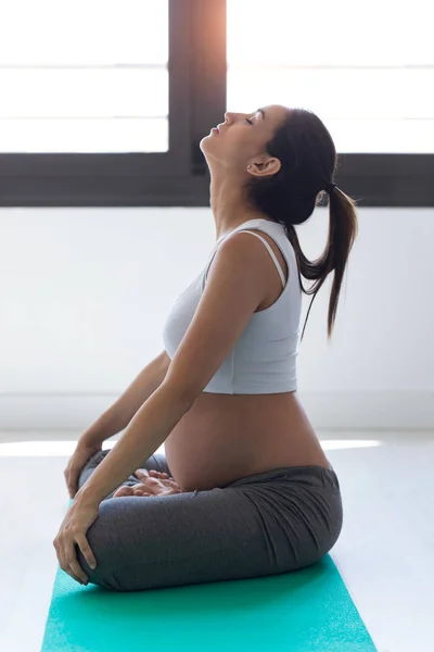 Mujer embarazada bastante joven estirándose después de hacer ejercicios de pilates en el aula de pre-parto . —  Fotos de Stock