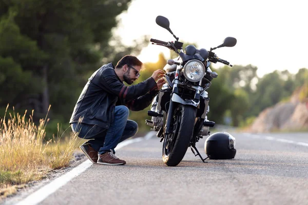Jeune homme motard vérifier sa moto avant de la conduire sur la route . — Photo
