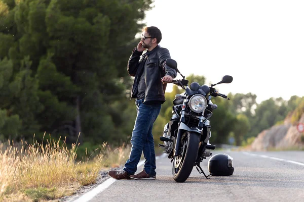 Homme motard parlant au téléphone à l'assurance de sa moto après avoir subi une panne sur la route . — Photo