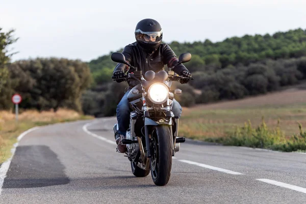 Joven ciclista divirtiéndose conduciendo la carretera vacía en un viaje en motocicleta . — Foto de Stock