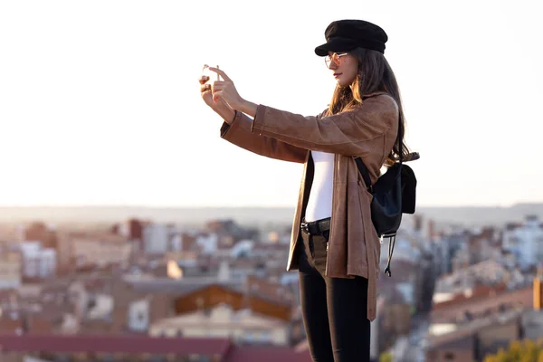 Pretty young woman taking photographs of sunset on the rooftop. — Stock Photo, Image