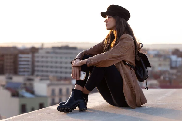 Söt ung kvinna njuter av tid och solnedgång medan du sitter på taket. — Stockfoto