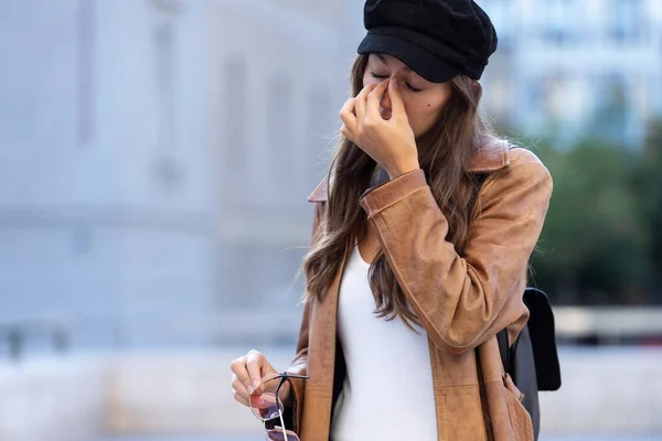 Schmerzhafte junge Frau leidet unter Kopfschmerzen, während sie auf der Straße steht. — Stockfoto