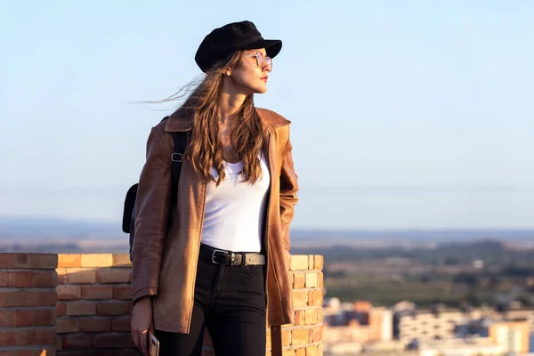 Mujer joven y bonita mirando al atardecer mientras está de pie en la azotea . — Foto de Stock