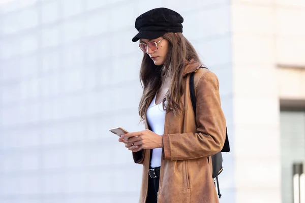 Söt ung kvinna använder sin mobiltelefon när hon står på gatan. — Stockfoto