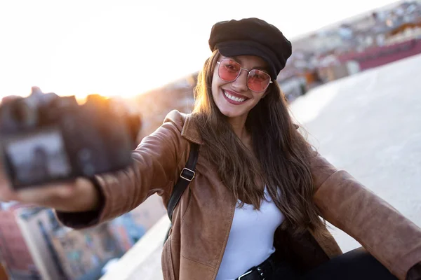 Ładna młoda kobieta robi selfie z aparatem podczas siedzenia na dachu. — Zdjęcie stockowe