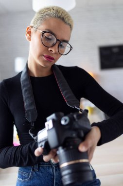 Modern genç girişimci kadın ofiste otururken kamerada son fotoğraflarını inceliyor..