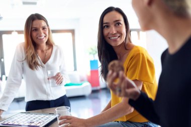 Üç genç girişimci kadın ara verip ofiste kahvaltı yapıyor..