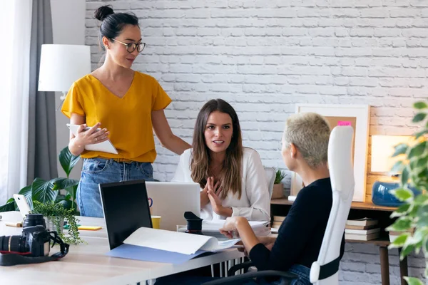 Tre moderna kvinnliga entreprenörer som pratar om nya idéer till nästa arbete på en gemensam arbetsplats. — Stockfoto