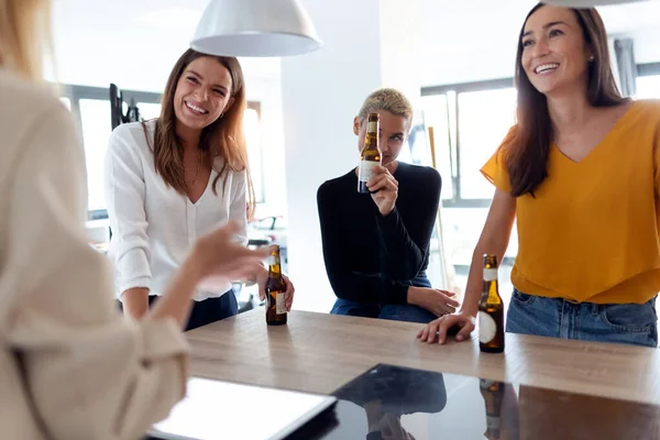 Squadra di giovani imprenditrici che festeggiano un successo bevendo birra in ufficio — Foto Stock
