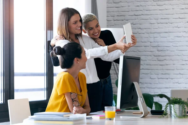 사무실에서 일하면서 디지털 태블릿으로 셀카를 찍고 있는 현대 사업가 세 명. — 스톡 사진
