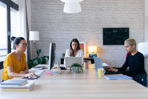 Tre moderna entreprenörer kvinnor som arbetar med nya idéer i co-working utrymme. — Stockfoto