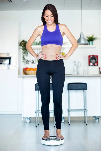 Mujer joven y saludable, feliz de ver que ha perdido peso en la escala de peso en casa . —  Fotos de Stock