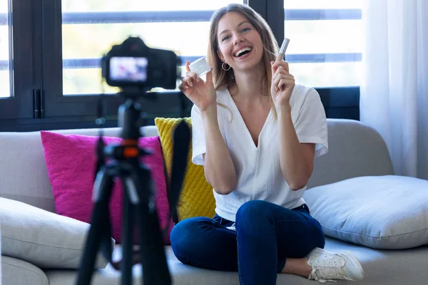 Hübsche junge Bloggerin hält Schönheitsprodukte in der Hand und lächelt, während sie Social-Media-Videos dreht — Stockfoto
