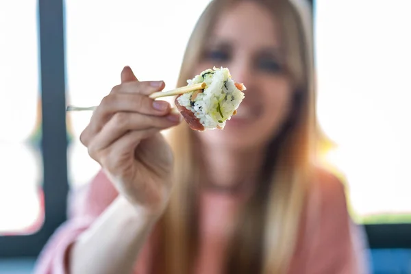 Skjuten Söt Ung Kvinna Visar Sushi Till Kameran Medan Sitter — Stockfoto