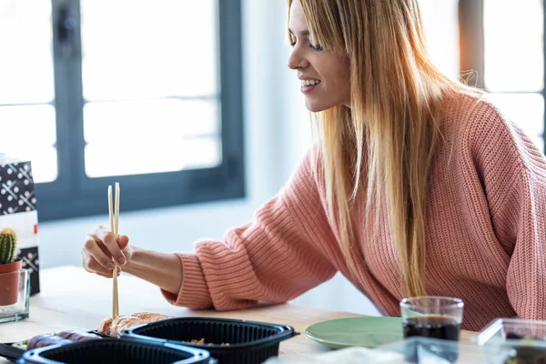 オフィスの窓の前に座っている彼女の寿司ランチを保存かなり若い女性のショット — ストック写真