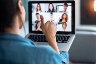 İş kadınlarının video görüşmesi ve evdeki kanepede otururken internet brifinginde başparmağını göstermesi..
