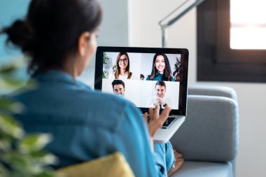 İş kadınlarının çeşitli meslektaşlarıyla evdeki kanepede dizüstü bilgisayarla yaptıkları online brifingde video konuşmalarının arka planı..